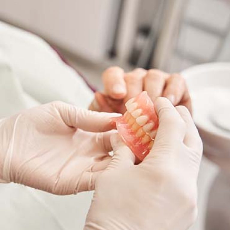 Its my new teeth. Cropped view of the dentist showing to senior grey haired patient teeth dentures while working at the dental clinic. Man sharing satisfaction smile